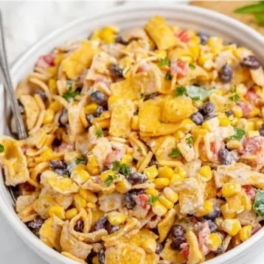 Bowl of colorful Frito Corn Salad with ingredients like corn, cheese, and Fritos.