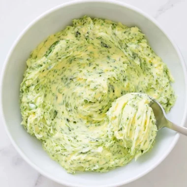 Basil pesto butter spread on fresh bread with a garnish of basil leaves