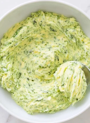 Basil pesto butter spread on fresh bread with a garnish of basil leaves