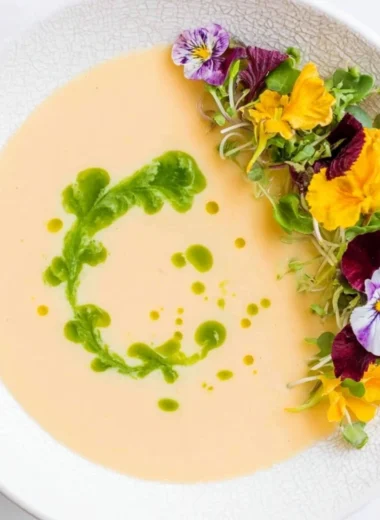 Bowl of chilled peach soup garnished with mint leaves