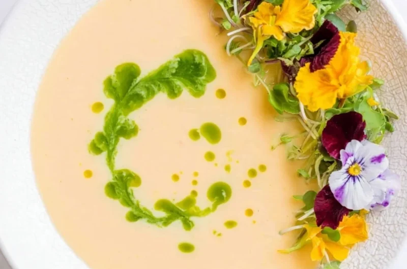 Bowl of chilled peach soup garnished with mint leaves