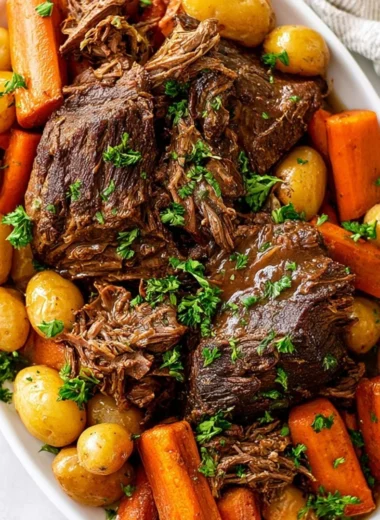 Delicious crock pot pot roast with vegetables and herbs in a slow cooker.