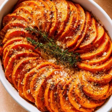 Bowl of Garlic Parmesan Roasted Sweet Potatoes garnished with herbs