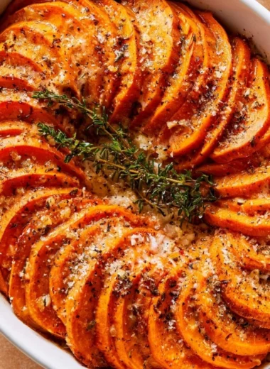 Bowl of Garlic Parmesan Roasted Sweet Potatoes garnished with herbs