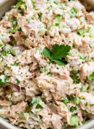 Healthy tuna salad with fresh vegetables and dressing served in a bowl.