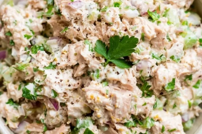 Healthy tuna salad with fresh vegetables and dressing served in a bowl.