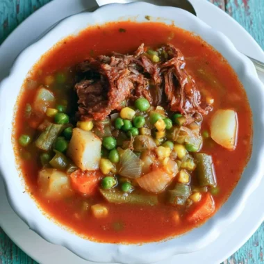 A bowl of hearty vegetable beef soup with colorful vegetables and tender beef pieces.