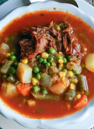 A bowl of hearty vegetable beef soup with colorful vegetables and tender beef pieces.