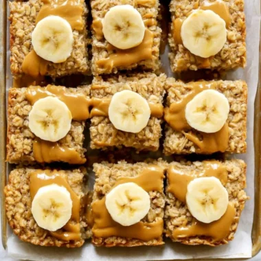 Peanut butter banana baked oatmeal in a bowl, topped with banana slices and peanut butter.