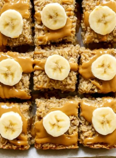 Peanut butter banana baked oatmeal in a bowl, topped with banana slices and peanut butter.
