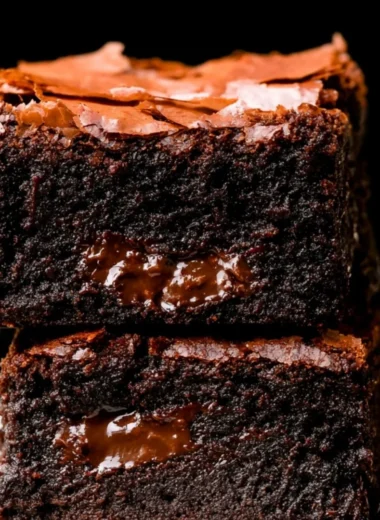 Ultimate fudgy brownies topped with chocolate and served on a rustic plate.