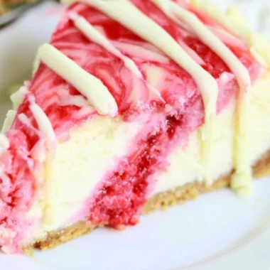 Delicious white chocolate raspberry swirl cheesecake with berry topping