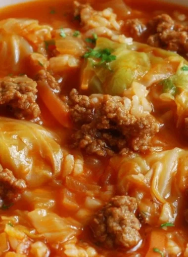 A bowl of homemade cabbage roll soup garnished with herbs and served with bread.