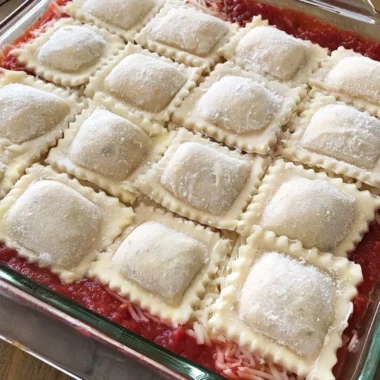 Cozy baked ravioli casserole topped with cheese and herbs in a baking dish