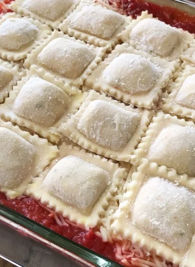 Cozy baked ravioli casserole topped with cheese and herbs in a baking dish