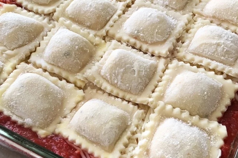 Cozy baked ravioli casserole topped with cheese and herbs in a baking dish