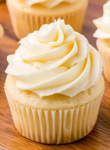 Cozy vanilla cupcakes topped with creamy frosting on a rustic wooden table.