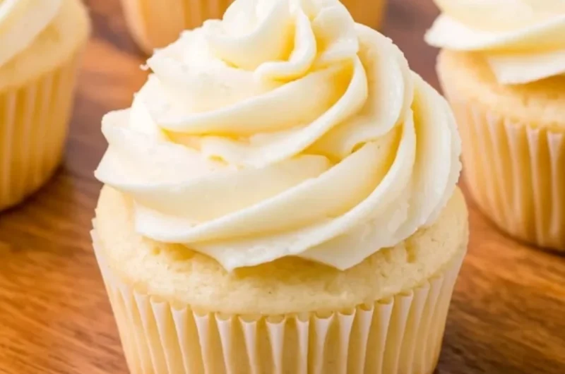 Cozy vanilla cupcakes topped with creamy frosting on a rustic wooden table.