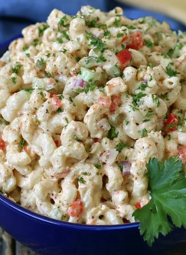 Creamy macaroni salad served in a bowl, garnished with herbs and vegetables