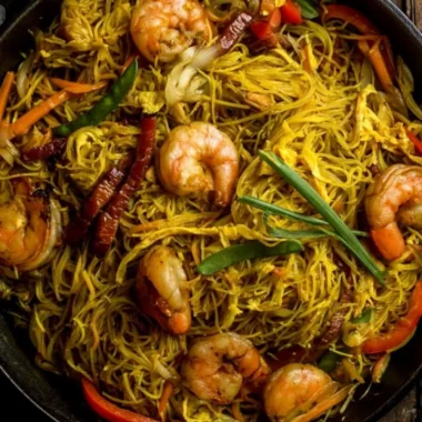 Delicious Singapore Noodles recipe served in a bowl with fresh vegetables.