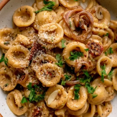 Bowl of cozy caramelized onion pasta topped with herbs and cheese