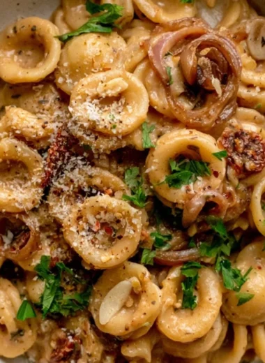 Bowl of cozy caramelized onion pasta topped with herbs and cheese