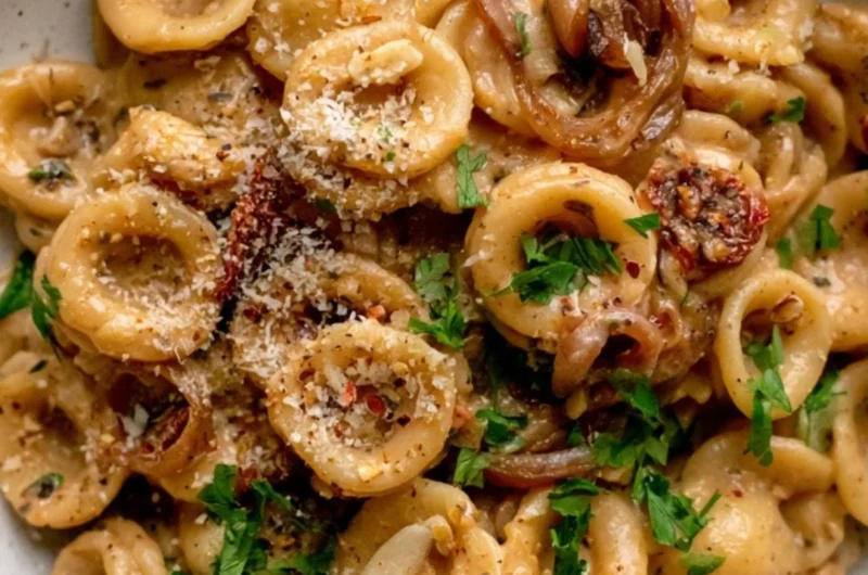 Bowl of cozy caramelized onion pasta topped with herbs and cheese