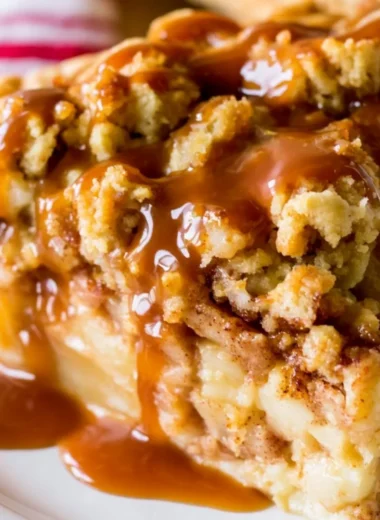 Dutch Caramel Apple Pie with caramel drizzle and apple slices on a wooden table.